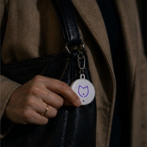 Close-up of a hand discreetly pressing the Silncy button on a bag strap